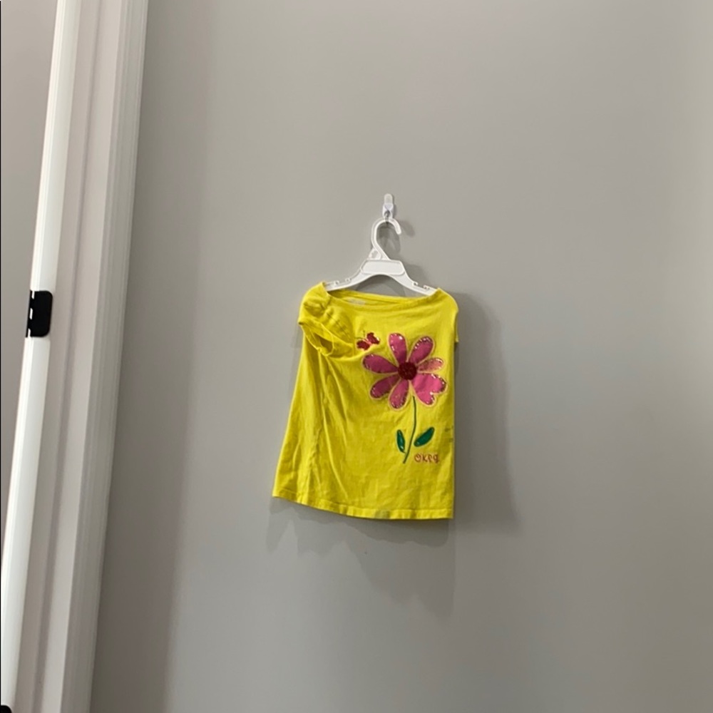 It is a yellow shirt with a flower on it